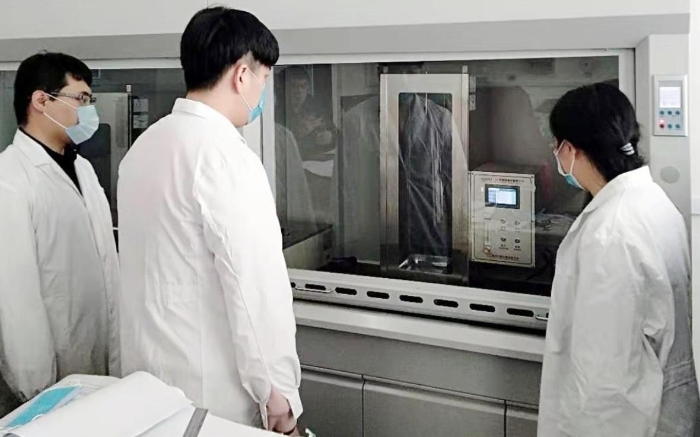 圖為吉林器械所檢驗人員開展疫情防護用品的阻燃試驗。