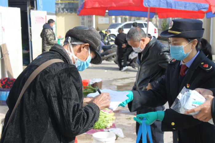 圖為鷹潭市市場監(jiān)管局工作人員向經營戶發(fā)放口罩。