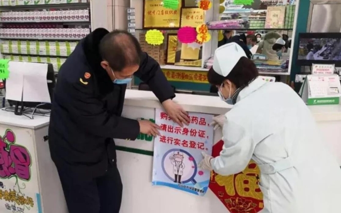 赤峰市紅山區(qū)市場監(jiān)管局監(jiān)管人員正在藥店張貼“實(shí)名登記購買退燒藥”宣傳海報。（赤峰市市場監(jiān)管局供圖）
