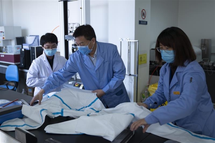 圖為趙玉杰（中）檢查醫(yī)用防護(hù)服應(yīng)急檢測(cè)工作。