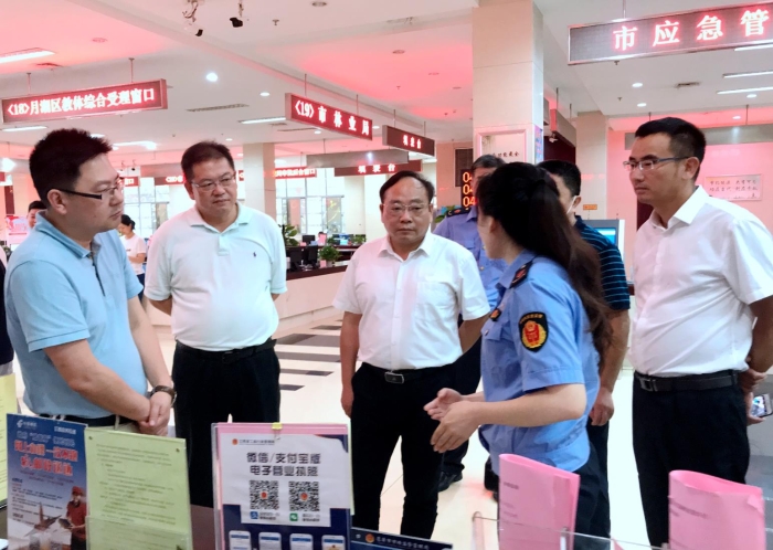 上官新晨（左三）在鷹潭市行政服務(wù)中心詳細(xì)了解“一照含證”改革情況。