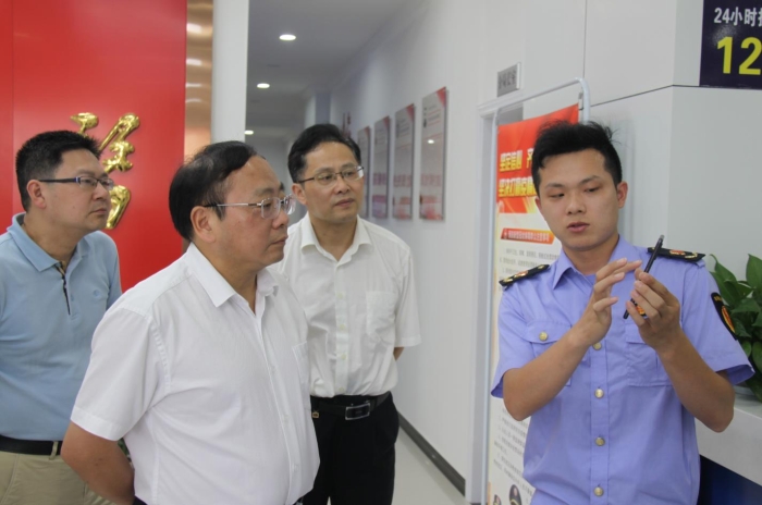 上官新晨（左二）在鷹潭市局東湖分局觀看基層執(zhí)法人員演示如何運(yùn)用智慧市場(chǎng)監(jiān)管網(wǎng)格化管理平臺(tái)開展監(jiān)督檢查工作等情況。