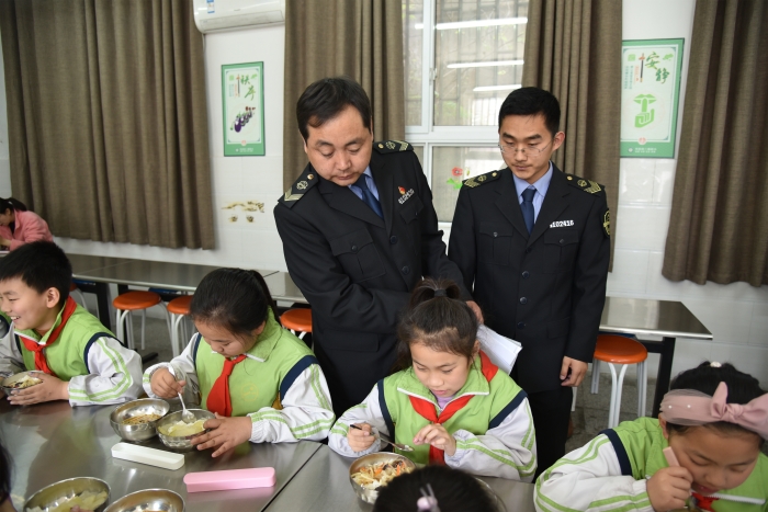 圖為執(zhí)法人員檢查食堂食品安全情況。