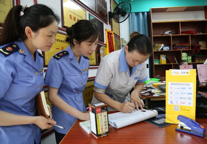 圖為執(zhí)法人員查看網(wǎng)絡(luò)藥品銷(xiāo)售登記，核對(duì)處方藥處方單。