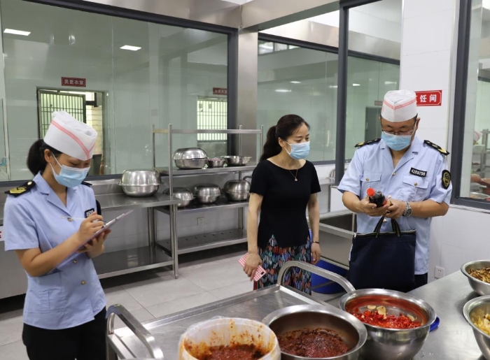 圖為執(zhí)法人員在檢查學(xué)校食堂加工制作情況。