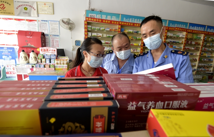 圖為執(zhí)法人員在一家藥店檢查中成藥質(zhì)量。