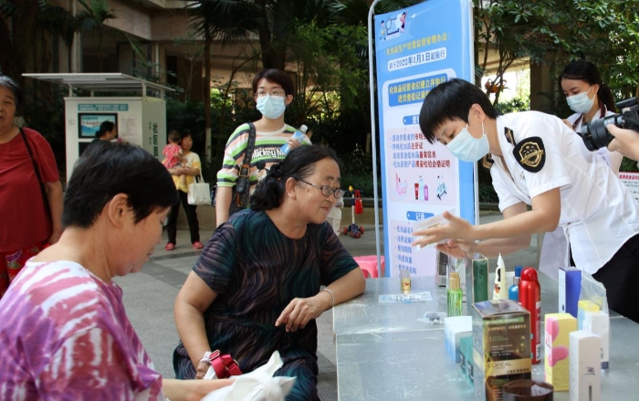 圖為檢驗(yàn)人員在為群眾現(xiàn)場講解辨別假冒偽劣化妝品的方法。（程奇 攝）