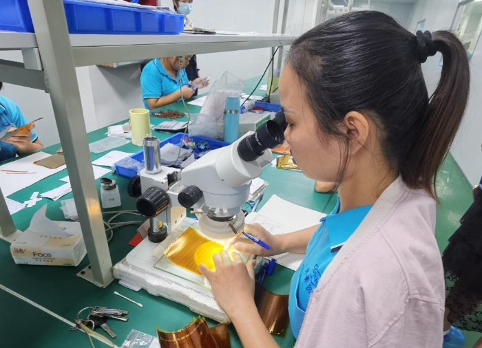 開(kāi)蒙醫(yī)療員工在用顯微鏡檢查人體成分分析儀芯片上的箔片集成電路是否有缺陷。