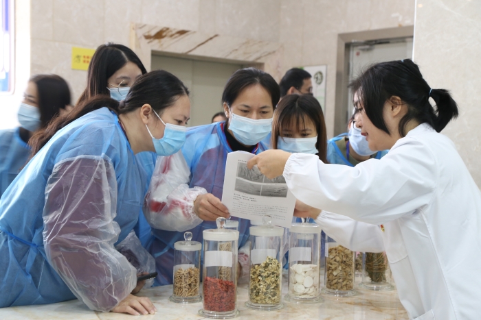 圖為工作人員為市民代表講解中藥材真?zhèn)舞b別知識。