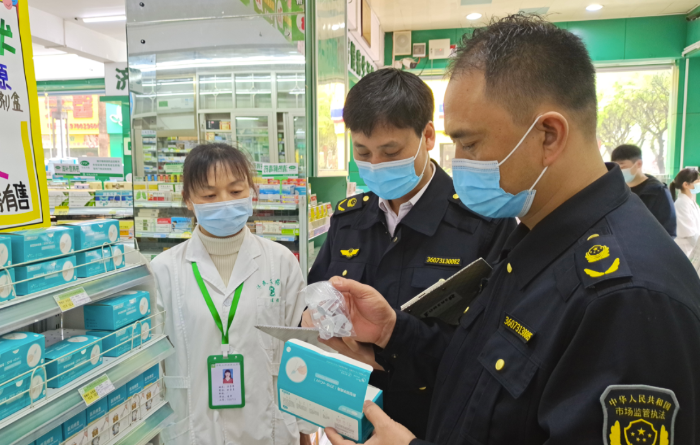 圖為執(zhí)法人員在一藥店查看抗原檢測(cè)試劑材料。