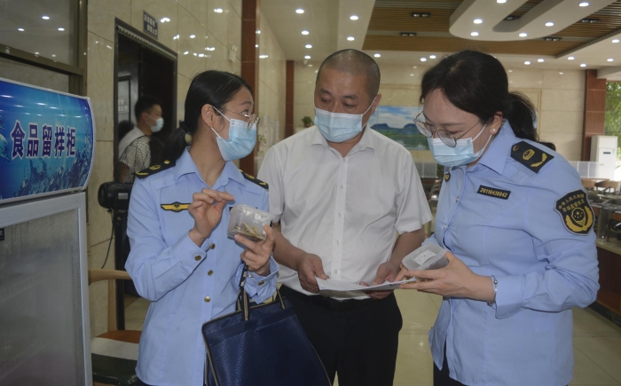 圖為執(zhí)法人員在食品檢查留樣情況。
