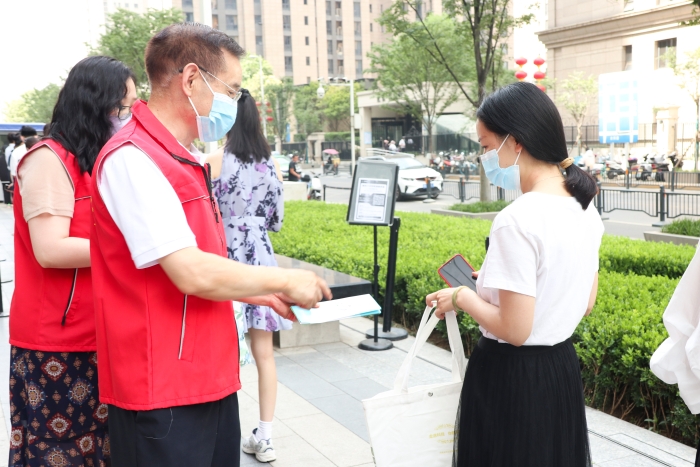 圖為藥監(jiān)系統(tǒng)志愿者為排隊等待檢測的居民發(fā)放科普抗疫小禮包，并為居民開展藥品安全科普，耐心解答居民用藥、用械安全方面的疑問和咨詢。（郝曉靜攝）