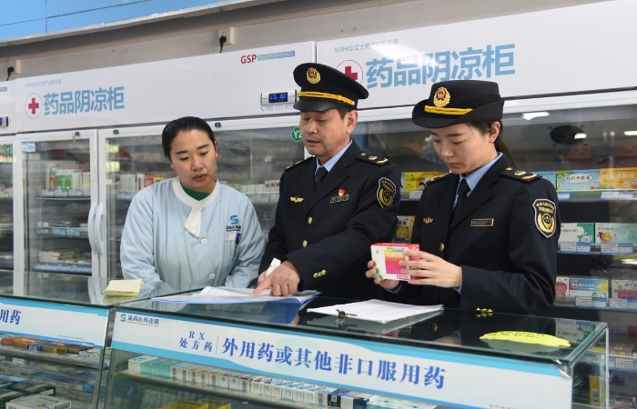圖為執(zhí)法人員在一家藥品經(jīng)營企業(yè)檢查藥品采購和陰涼藥品儲存記錄情況。
