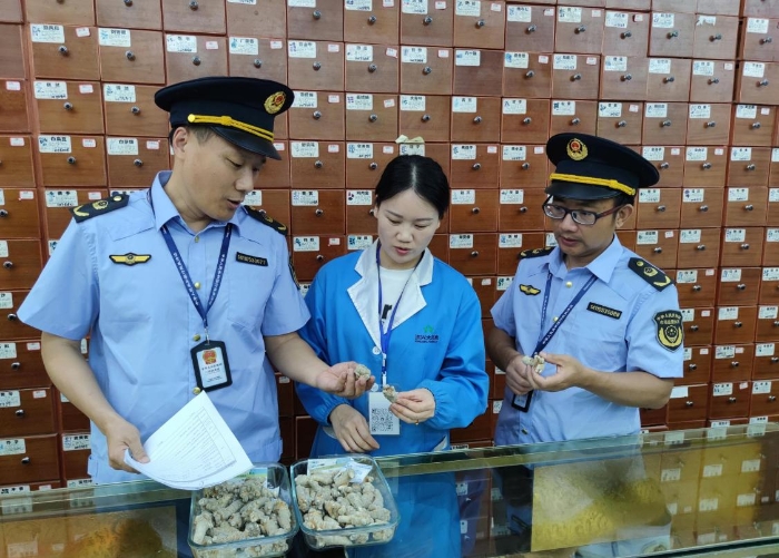 圖為執(zhí)法人員在一零售藥店檢查中藥飲片質(zhì)量情況。
