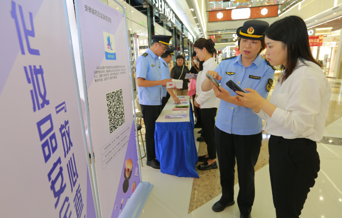 圖為9月13日，該局執(zhí)法人員正在指導化妝品經(jīng)營者安裝使用該APP。