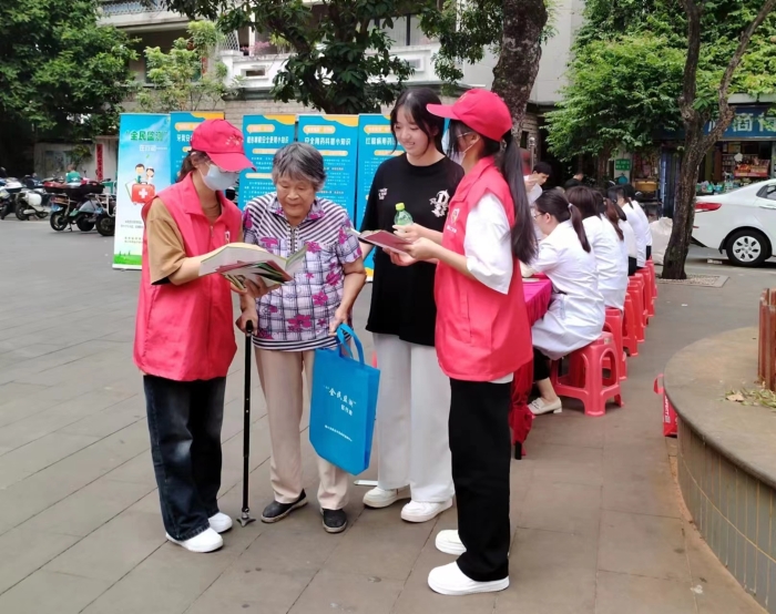 圖為工作人員向過往居民發(fā)放“全民監(jiān)測”科普宣傳資料。
