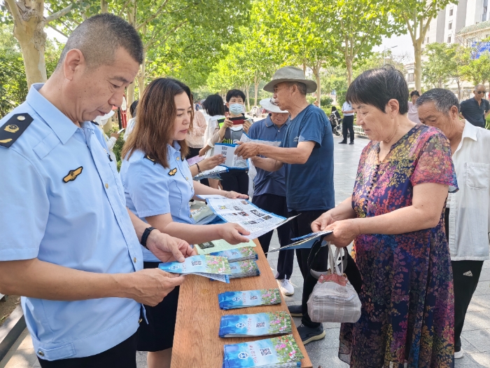 圖為工作人員向群眾發(fā)放禁毒宣傳手冊。